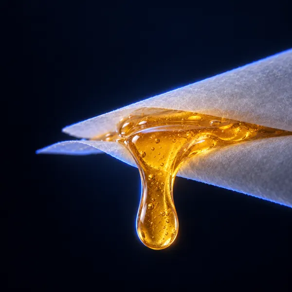 Goccia di live rosin ambrato che cola tra due fogli di carta da forno