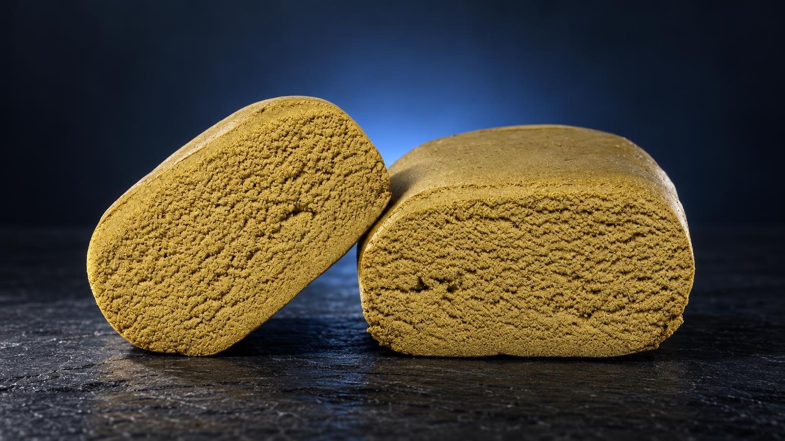 Due blocchi di Ice O Lator di colore giallo dorato con texture granulosa, posizionati su superficie scura con sfondo blu